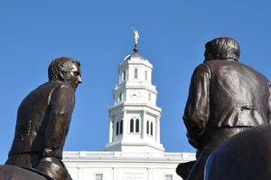A photo of a tower in Nauvoo, Illinois seen between two statues.